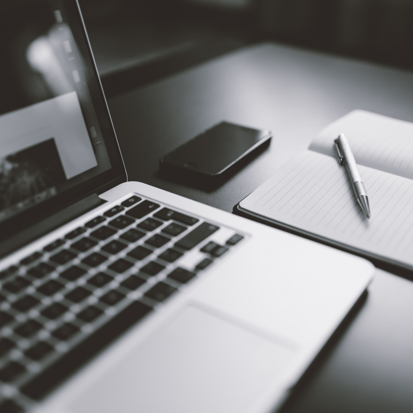 A laptop and pen and paper that represent investing in communications.