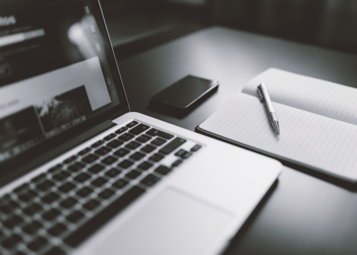 A laptop and pen and paper that represent investing in communications.